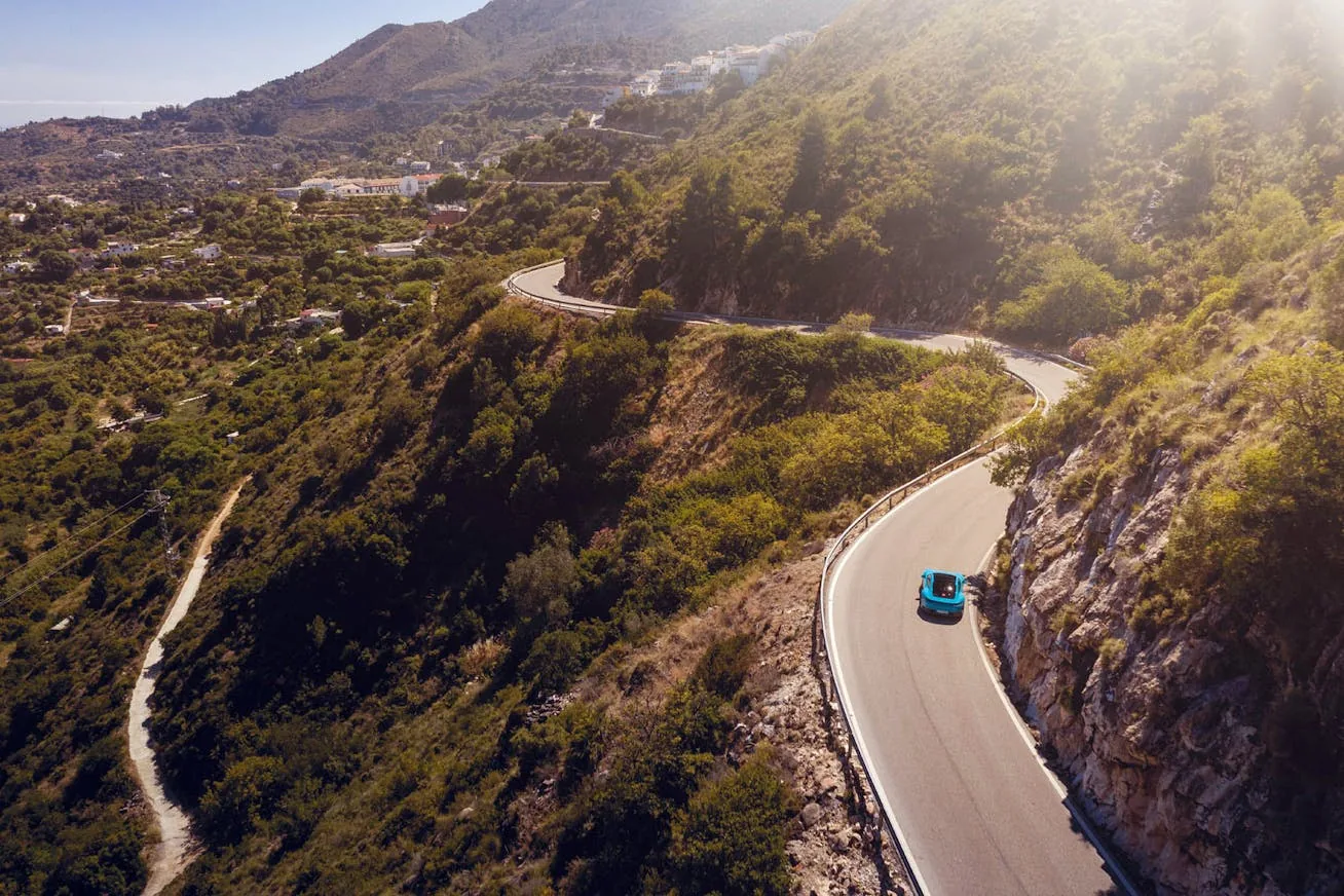 A sports car following a winding road through the hills